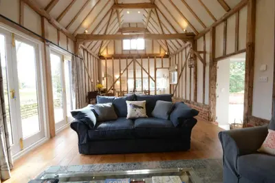 a living room with a blue couch in a barn at Bird Cottage, Burgh in Grundisburgh