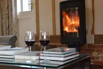 two glasses of wine on a table in front of a fireplace at Bird Cottage, Burgh in Grundisburgh