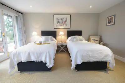 a bedroom with two beds with white comforters at Bird Cottage, Burgh in Grundisburgh