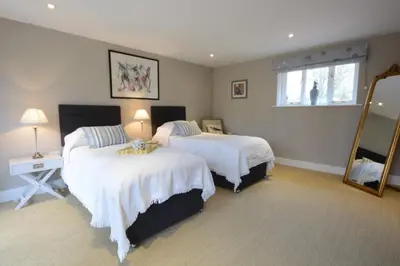 a bedroom with two beds and a mirror at Bird Cottage, Burgh in Grundisburgh