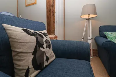a blue couch with a pillow with a dog on it at 1 The Old Coach House in Laxfield
