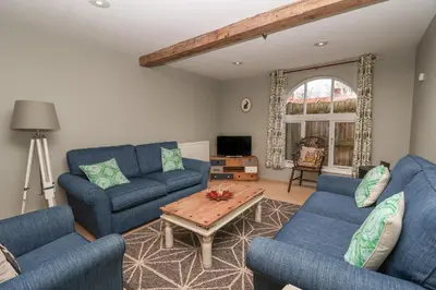 a living room with blue couches and a coffee table at 1 The Old Coach House in Laxfield