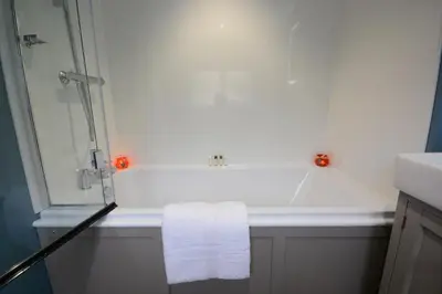 a bathroom with a bath tub with a towel at 1 The Old Coach House in Laxfield