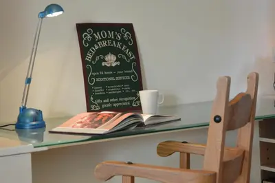 a book on a desk with a cup and a chair at 2 The Bays, Thorpeness in Thorpeness