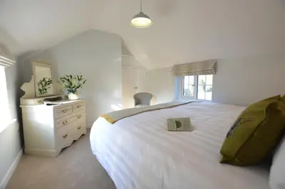 a bedroom with a white bed with a book on it at Little Turnpike Cottage, Melton in Woodbridge