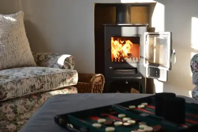 a living room with a fireplace and a table with agamuitous at Little Turnpike Cottage, Melton in Woodbridge