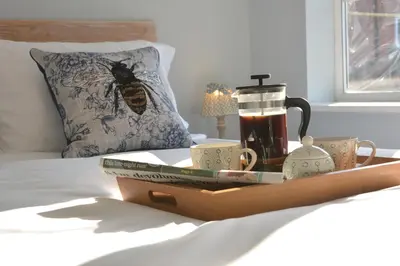 a tray with a tea set on a bed at Little Turnpike Cottage, Melton in Woodbridge