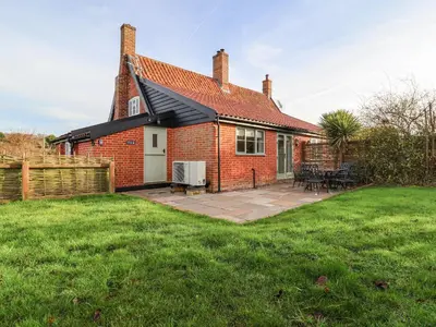 a red brick house with a patio in the yard at Pudding Cottage, Westleton in Westleton