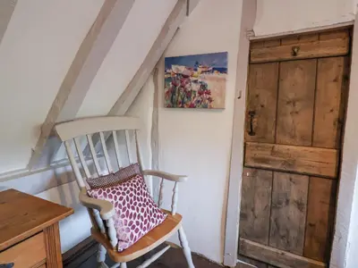 a wooden chair with a pillow on it next to a door at Pudding Cottage, Westleton in Westleton
