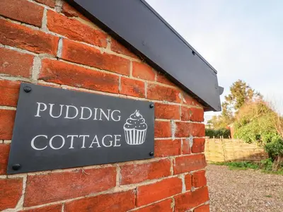 a sign on the side of a brick wall at Pudding Cottage, Westleton in Westleton