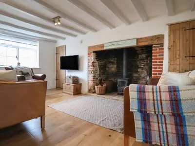 a living room with a fireplace and a couch at Pudding Cottage, Westleton in Westleton