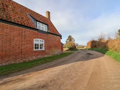 a dirt road next to a brick building at Pudding Cottage, Westleton in Westleton