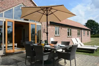a table and chairs with an umbrella on a patio at The Mulberry, nr Bungay in Bungay