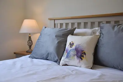 a bed with four pillows and a lamp on a table at The Mulberry, nr Bungay in Bungay