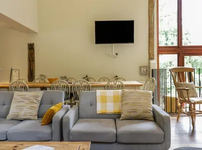 a living room with a couch and a table with chairs at Quill Farm Barn in Campsea Ashe