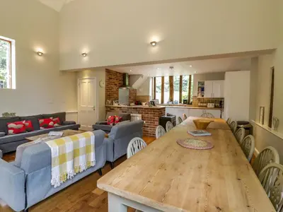 a living room with a wooden table and a kitchen at Quill Farm Barn in Campsea Ashe