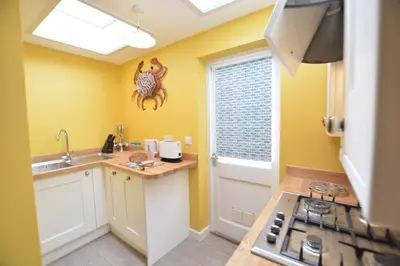 a kitchen with yellow walls and a sink and a stove at Alinka, Aldeburgh in Aldeburgh