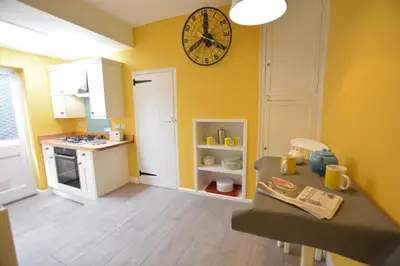 a kitchen with a clock on the wall and a table at Alinka, Aldeburgh in Aldeburgh