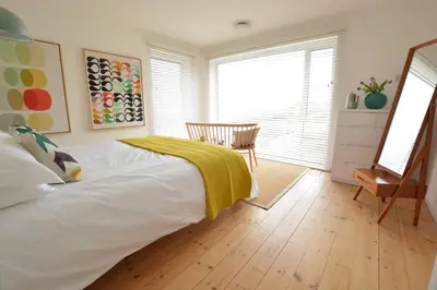 a bedroom with a bed with a yellow blanket on it at Aldeburgh Lodge Gardens in Aldeburgh