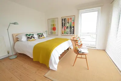 a bedroom with a bed with a yellow blanket and a chair at Aldeburgh Lodge Gardens in Aldeburgh