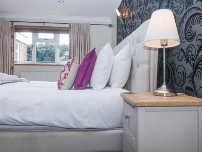 a bedroom with a white bed with purple pillows at Little Wissett, Aldeburgh in Aldeburgh