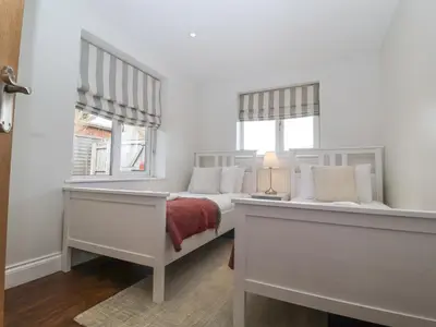 a white bedroom with a bed and two windows at Little Wissett, Aldeburgh in Aldeburgh