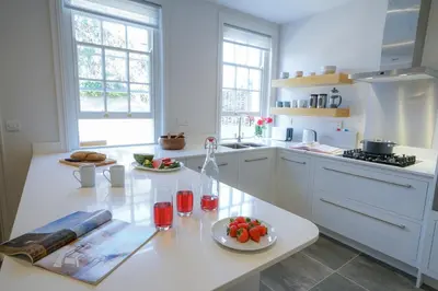 a white kitchen with a table with a plate of fruit on it at 10 Church Walk, Aldeburgh in Aldeburgh