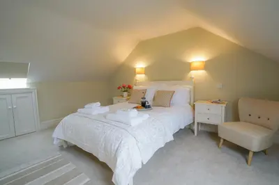 a bedroom with a large bed and a chair at 10 Church Walk, Aldeburgh in Aldeburgh