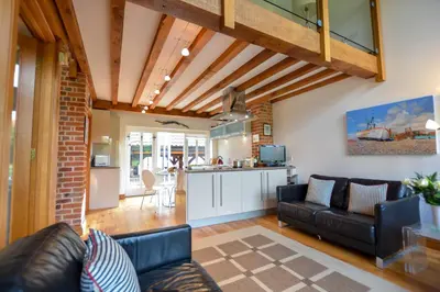a living room with a couch and a kitchen at Two Chantry Barns, Orford in Orford
