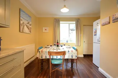 a kitchen with a table with chairs and a refrigerator at Gosfield Cottage, Aldeburgh in Aldeburgh