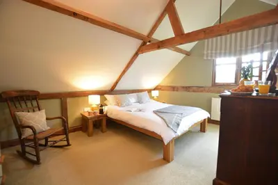a bedroom with a bed and a chair in a attic at Wheelwright's Barn in Halesworth