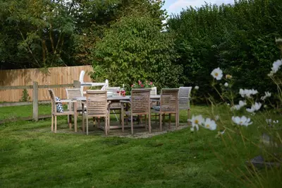 a wooden table and chairs in a yard at Wheelwright's Barn in Halesworth