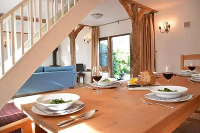 a dining room with a wooden table with glasses of wine at Wheelwright's Barn in Halesworth