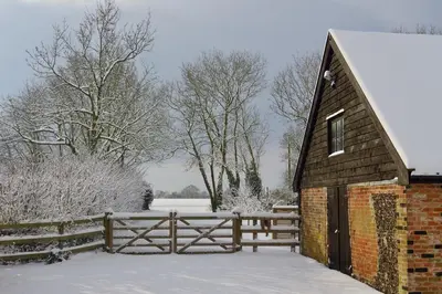 a barn in the snow with a fence at Manor House Barn, Peasenhall in Peasenhall