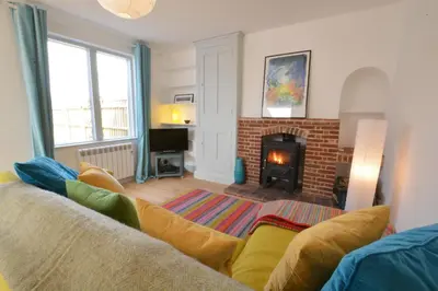 a living room with a couch and a fireplace at 2 Pink Cottages, Aldeburgh in Aldeburgh
