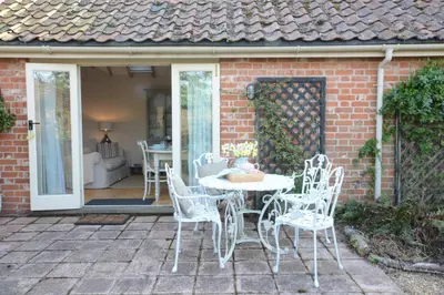 a white table and chairs on a patio at The Nookery at Snape Hall in Snape