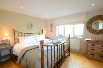 a bedroom with a large bed and a mirror at The Nookery at Snape Hall in Snape
