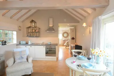 a kitchen and living room with a table and chairs at The Nookery at Snape Hall in Snape