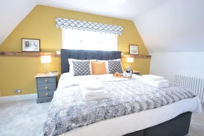 a bedroom with a large bed with towels on it at Woodland Cottage, Great Glemham in Framlingham