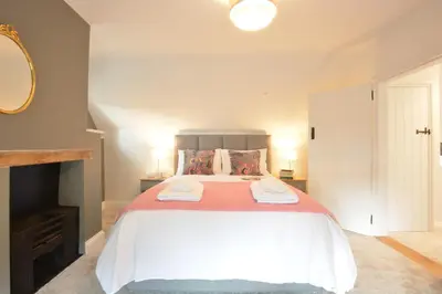 a bedroom with a large bed with two towels on it at Woodland Cottage, Great Glemham in Framlingham