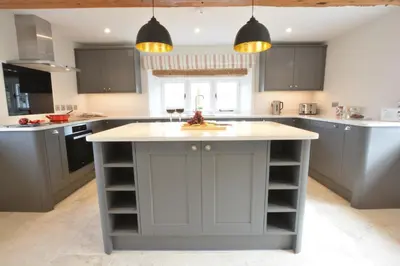 a kitchen with gray cabinets and a white counter top at Woodland Cottage, Great Glemham in Framlingham