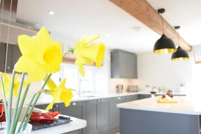a kitchen with yellow flowers in a vase on a counter at Woodland Cottage, Great Glemham in Framlingham