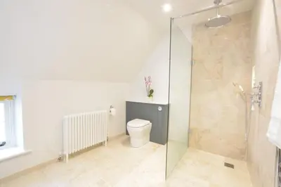 a bathroom with a toilet and a glass shower stall at Woodland Cottage, Great Glemham in Framlingham