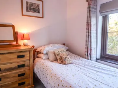 a bedroom with a bed and a dresser and a window at Pine Cottage in Woodbridge