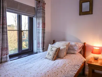 a bedroom with a bed and a large window at Pine Cottage in Woodbridge