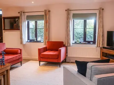 a living room with red chairs and windows at Pine Cottage in Woodbridge
