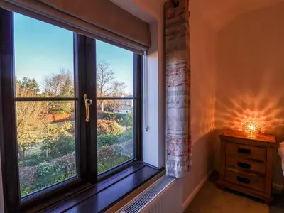 a bedroom with a window with a view at Pine Cottage in Woodbridge