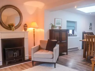 a living room with a chair and a mirror at Pine Cottage in Woodbridge