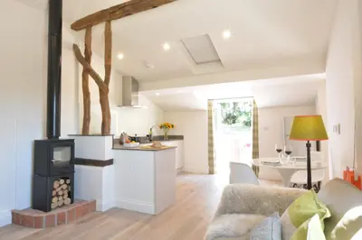 a kitchen and living room with a stove at Carriage House, Bruisyard in Framlingham