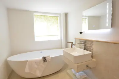a white bathroom with a tub and a sink at Carriage House, Bruisyard in Framlingham